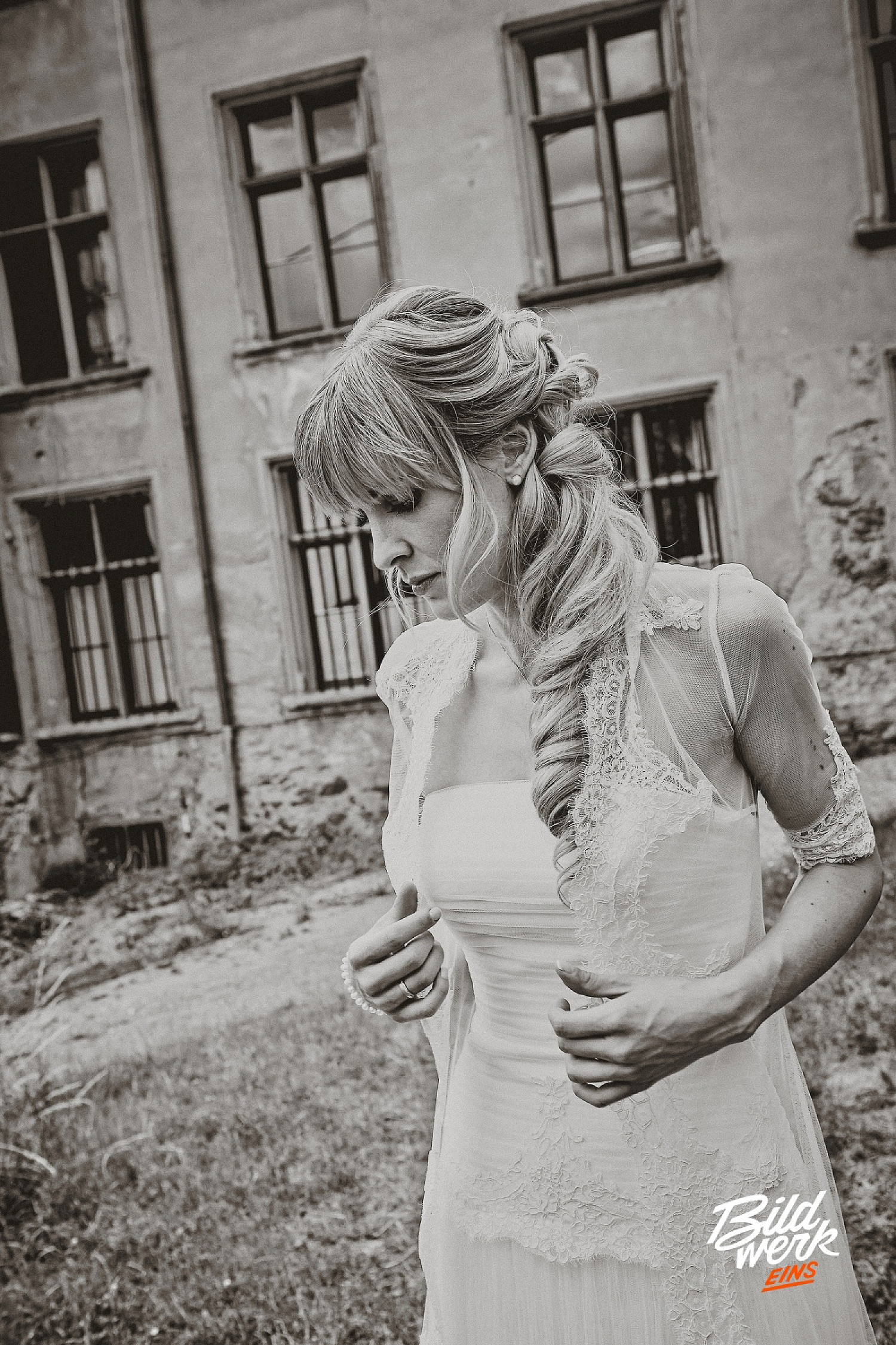 Ein traumhaftes Brautportrait. Hier steht die Braut im Mittelpunkt. Das Bild ist in einem alten Schloss entstanden. Sie trägt ein klassisches weißes Kleid mit Spitze. Sie schaut verträumt zu Boden.